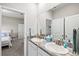 Bright bathroom features double sinks with granite countertops and a view into the nearby bedroom at 17547 Cantarina Cv, Bradenton, FL 34211