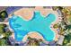 Aerial view of a uniquely shaped swimming pool surrounded by lounge chairs and lush landscaping at 17547 Cantarina Cv, Bradenton, FL 34211