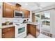 Well-lit kitchen with wood cabinets, white appliances, and backyard access at 2105 19Th W St, Bradenton, FL 34205