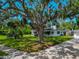 Expansive front yard with a large oak tree providing shade to the home with manicured lawn at 326 25Th W St, Bradenton, FL 34205