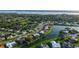 A high-angle aerial view showcases a lakeside home with an orange roof, near a tranquil pond and verdant landscape at 387 Eden Dr Dr, Englewood, FL 34223