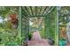 Beautifully landscaped walkway through an arbor, leading to a serene water view and dock area at 387 Eden Dr Dr, Englewood, FL 34223