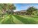 Expansive backyard with verdant lawn, mature trees, and a view of the screened pool area at 387 Eden Dr Dr, Englewood, FL 34223