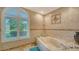 Bathroom with an arched window and tile flooring surrounding a soaking tub at 387 Eden Dr Dr, Englewood, FL 34223
