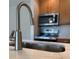 Close-up view of modern sink and stone countertop in a kitchen with wood cabinets at 4037 Crockers Lake Blvd # 24, Sarasota, FL 34238