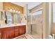 Bright bathroom featuring double sinks, wood cabinets, and a glass-enclosed shower at 4121 Reflections Pkwy, Sarasota, FL 34233