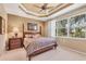 Cozy main bedroom with a four-poster bed, a large window, and a decorative tray ceiling at 4121 Reflections Pkwy, Sarasota, FL 34233