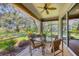 Relaxing screened-in patio with ceiling fan, table set, and views of the green backyard at 4121 Reflections Pkwy, Sarasota, FL 34233