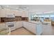 Well-lit kitchen with granite countertops, white cabinets, and appliances adjacent to a dining and sitting area at 4310 Falmouth Dr # 307, Longboat Key, FL 34228