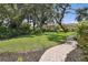 Landscaped backyard featuring mature trees, a stone walkway, and lush green grass create a peaceful retreat at 4696 Del Sol Blvd, Sarasota, FL 34243
