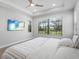 A primary bedroom features a flat screen TV, tray ceiling with a large window offering plenty of natural light at 4988 Fairhope Cir, Lakewood Ranch, FL 34211