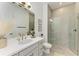Modern bathroom features a large mirror, white vanity, and glass shower with gray tiling and gold fixtures at 501 Maraviya Blvd, Nokomis, FL 34275