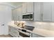 Close-up of kitchen featuring custom backsplash, modern oven, and gray cabinetry at 501 Maraviya Blvd, Nokomis, FL 34275