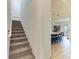 Carpeted staircase adjacent to an open floorplan featuring a kitchen island with seating under pendant lights at 501 Maraviya Blvd, Nokomis, FL 34275