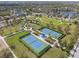 Aerial view of pristine tennis courts and lush landscaping with a covered picnic area in a Gathering-friendly community at 5047 Newport News Cir, Bradenton, FL 34211