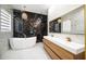 Modern bathroom featuring black marble accent wall, soaker tub, dual sink vanity, and chandelier lighting at 5074 Flagstone Dr, Sarasota, FL 34238