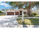 Charming single-story home with a well-manicured lawn and a three-car garage, beautifully shaded by a large tree at 5240 Silver Charm Ter, Wesley Chapel, FL 33544