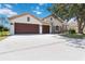 Attractive home featuring a three-car garage, stone accents, and lush landscaping, offering curb appeal and comfort at 5240 Silver Charm Ter, Wesley Chapel, FL 33544