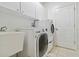 Bright laundry room featuring white washer and dryer, storage cabinets, and a utility sink at 5240 Silver Charm Ter, Wesley Chapel, FL 33544
