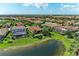 Aerial view of homes with red tiled roofs and green lawns nestled around a scenic pond in a sunny community at 5511 Foxfire Run, Lakewood Ranch, FL 34211