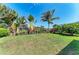 Landscaped backyard featuring green grass, tropical plants, and a black metal fence overlooking a pond at 5511 Foxfire Run, Lakewood Ranch, FL 34211