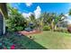 Lush backyard featuring a well-manicured lawn, tropical plants, and outdoor lounge chairs at 5511 Foxfire Run, Lakewood Ranch, FL 34211