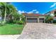 Paver driveway leading to a lovely two-car garage, lush landscaping, and stone accents on a sunny day at 5511 Foxfire Run, Lakewood Ranch, FL 34211