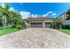 Paver driveway leading to a lovely two-car garage, lush landscaping, and stone accents on a sunny day at 5511 Foxfire Run, Lakewood Ranch, FL 34211