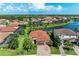 Beautifully landscaped home featuring a paver driveway, two-car garage, and a vibrant green lawn near a tranquil lake at 5511 Foxfire Run, Lakewood Ranch, FL 34211