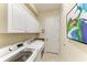 Laundry room equipped with washer, dryer, storage cabinets, and utility sink at 5511 Foxfire Run, Lakewood Ranch, FL 34211