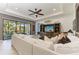 Bright living room featuring a white sofa, decorative ceiling fan, and large entertainment center at 5511 Foxfire Run, Lakewood Ranch, FL 34211