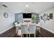 Dining room featuring a white table, gray upholstered chairs, dark wood floors, and a modern fireplace with a wall-mounted TV at 5565 Sweetwater Oak Dr, Sarasota, FL 34232