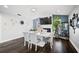 Bright dining room with white table, grey chairs, hardwood floors, and a modern fireplace with mounted TV at 5565 Sweetwater Oak Dr, Sarasota, FL 34232