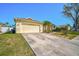 Exterior showcasing a spacious driveway leading to the attached garage, complemented by lush landscaping and a palm tree at 5565 Sweetwater Oak Dr, Sarasota, FL 34232