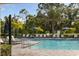 Community swimming pool with lounge chairs, umbrellas, clear blue water, and lush tropical landscaping for relaxation at 6239 Baywood Ct, Bradenton, FL 34211