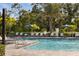 Community swimming pool with lounge chairs, umbrellas, clear blue water, and lush tropical landscaping for relaxation at 6239 Baywood Ct, Bradenton, FL 34211
