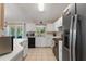 Bright kitchen with white cabinets, stainless steel appliances, tile flooring and views to backyard at 712 68Th W Ave, Bradenton, FL 34207