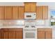 Kitchen featuring white appliances, wooden cabinets, white countertops, and tile floors at 7432 Birds Eye Ter, Bradenton, FL 34203