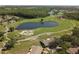 An aerial view displays an expansive community with a scenic pond and lush green space at 1111 Harefield Cir, Sun City Center, FL 33573