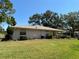 Well-maintained backyard with lush green lawn, mature trees, and a view of the home's exterior at 1111 Harefield Cir, Sun City Center, FL 33573