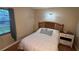 Cozy bedroom featuring a wooden headboard, a bedside table, and natural light from the window at 1111 Harefield Cir, Sun City Center, FL 33573