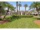 Well-manicured community entrance featuring lush greenery, palm trees, and a beautiful central fountain at 1111 Harefield Cir, Sun City Center, FL 33573