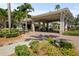 Elegant community entrance with a porte-cochere, lush landscaping, and manicured surroundings at 1111 Harefield Cir, Sun City Center, FL 33573