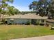 Charming home with lush landscaping, mature trees, and inviting front porch, creating a serene atmosphere at 1111 Harefield Cir, Sun City Center, FL 33573