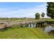 Charming view of a wooden bridge over a serene pond surrounded by lush greenery and neighborhood homes at 1111 Harefield Cir, Sun City Center, FL 33573