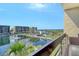 Balcony view featuring waterfront condos, a pond, and tropical landscaping against a blue sky at 1115 Gulf Of Mexico Dr # 304, Longboat Key, FL 34228