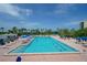 Beautiful community pool area with blue umbrellas and lounge chairs surrounded by palm trees at 1115 Gulf Of Mexico Dr # 304, Longboat Key, FL 34228
