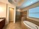 Bathroom with a soaking tub, a glass shower, neutral tile, and natural light at 119 Maraviya Blvd, Nokomis, FL 34275