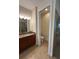 Bathroom with granite countertops, double sinks, dark cabinetry, and neutral tile flooring at 119 Maraviya Blvd, Nokomis, FL 34275