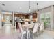 Dining room with light wood table and chairs, adjacent to kitchen with stainless steel appliances and dark cabinets at 12327 Halfmoon Lake Ter, Bradenton, FL 34211